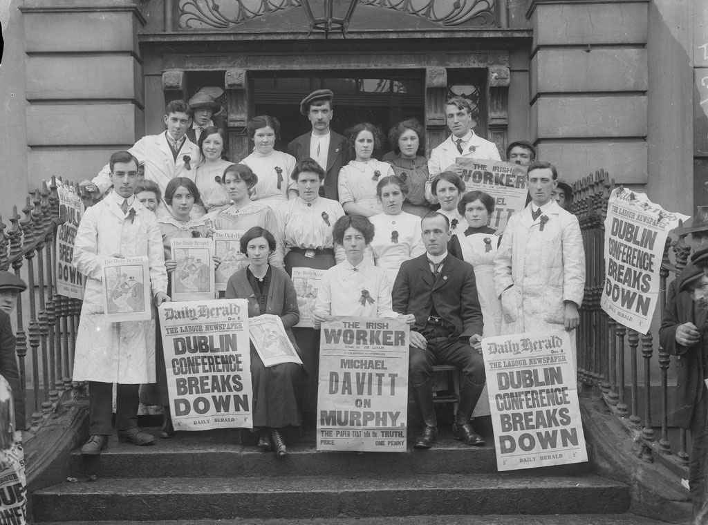 Workers on the steps of Liberty Hall carry news posters announcing the failure of the Dublin Peace Conference, December 1913. Front and centre, holding The Irish Worker poster, is Delia Larkin, sister of Jim Larkin and first General Secretary of the Irish Women Workers' Union, founded in 1911.