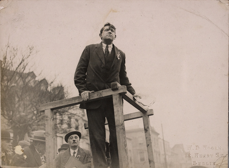Michael Collins speaking from a podium