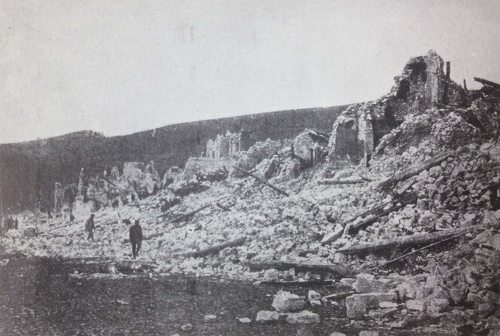 A scene in Avezzano. Survivors walk along a street that used to contain huge mansions; all of them have been reduced to rubble.