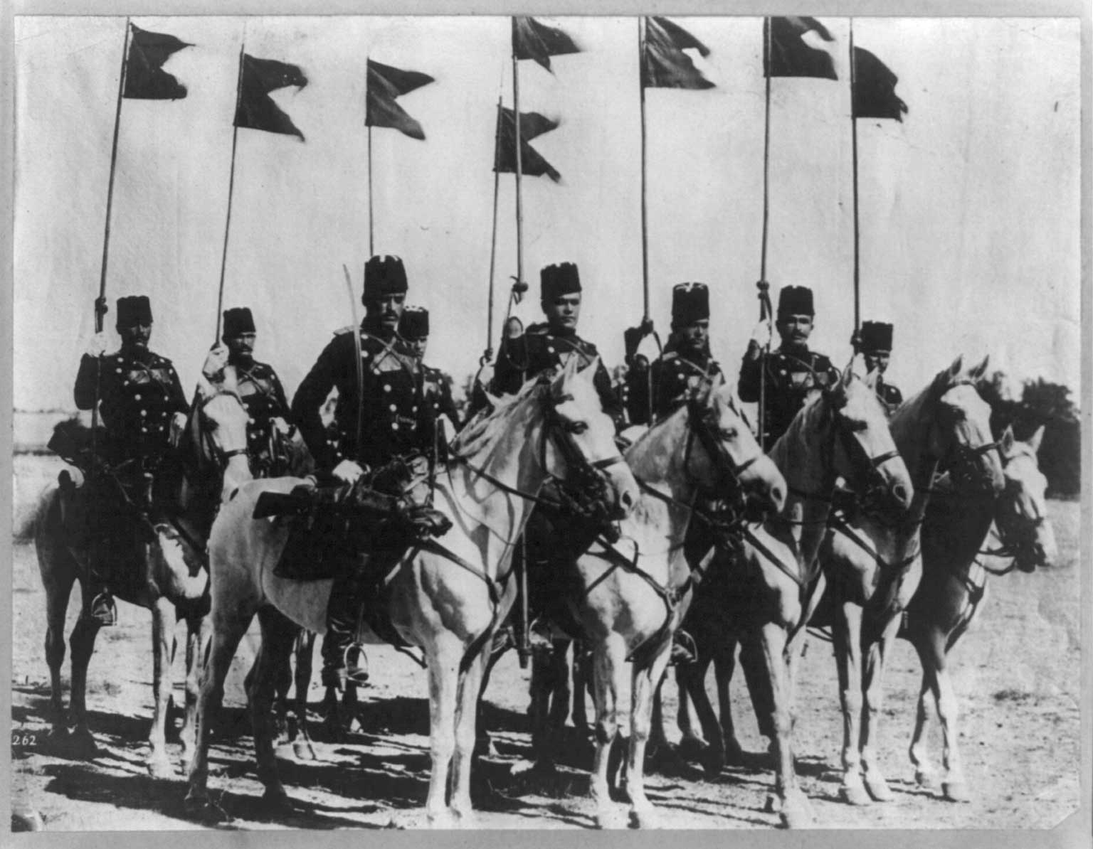Eight members of the Turkish cavalry on horseback with flags  ca. 1913. Reports from Bulgaria claim that Turkish troops have committed a series of atrocities in the country